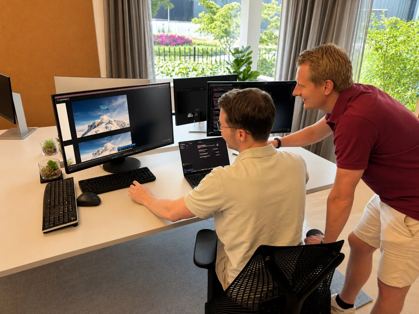 Twee TopDevs-developers werken samen achter dubbele schermen op kantoor